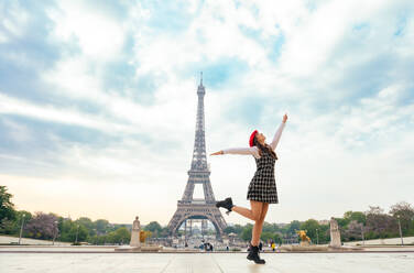 Junge Frau in rotem Hut und modischer Kleidung erkundet Paris und den Eiffelturm, während sie das Stadtzentrum und die Sehenswürdigkeiten genießt - DMDF06431