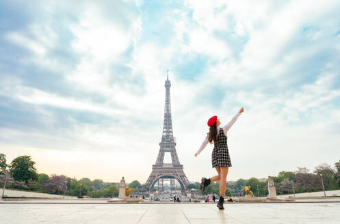 Eine junge Frau mit rotem Hut und modischer Kleidung besucht Paris und den Eiffelturm und genießt die Sehenswürdigkeiten der Stadt - DMDF06432