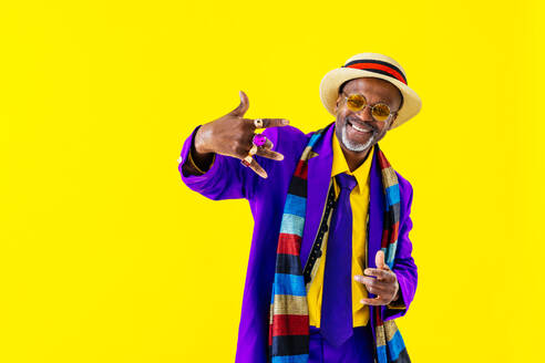 Stilvoller Rentner mit exzentrischer Mode auf farbenfrohem Hintergrund - ein lustiges Porträt eines coolen älteren Mannes - DMDF06454