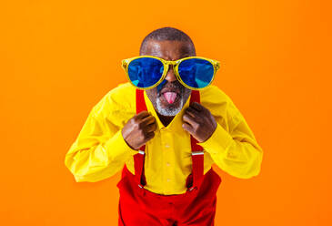 Cool senior man with fashionable clothing style portrait on colored background - Funny old male pensioner with eccentric style having fun - DMDF06457