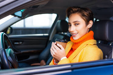 Beautiful young woman with short hair driving car in the city - Pretty caucasian female adult business woman wearing elegant suit going to work in the office - DMDF06473