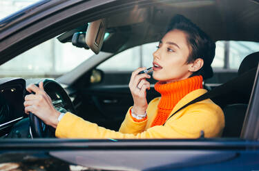 Beautiful young woman with short hair driving car in the city - Pretty caucasian female adult business woman wearing elegant suit going to work in the office - DMDF06475