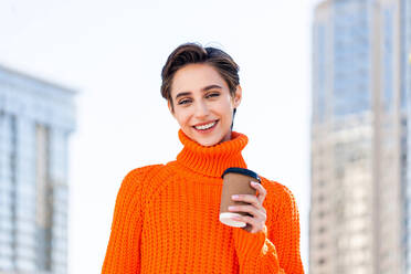 Beautiful young woman with short hair in the city - Pretty caucasian female adult business woman wearing winter sweater - DMDF06514