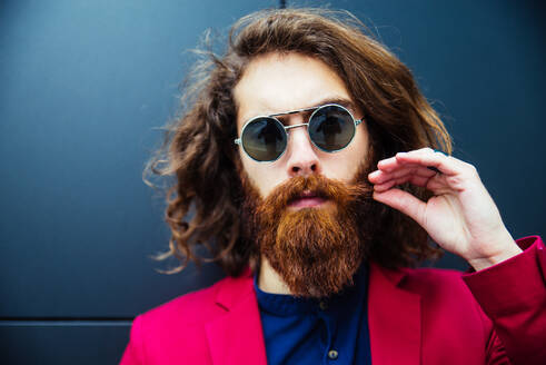 Fashion portrait of a young hipster man walking outdoors with a red formal suit - Unusual businessman going to work - DMDF06524