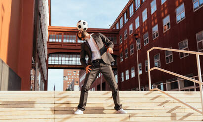 Bild eines Geschäftsmannes und eines Fußball-Freestyle-Spielers, der auf der Straße Tricks mit dem Ball macht. Konzept über Sport und Geschäftsleute - DMDF06538