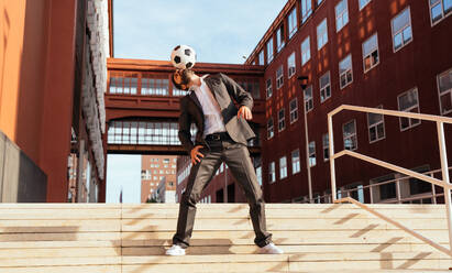 Image of a businessman and soccer freestyle player making tricks with the ball on the street. Concept about sport and business people - DMDF06538