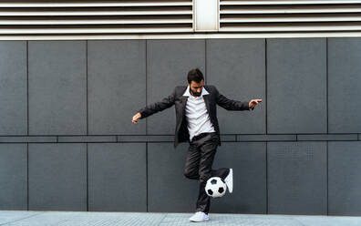 Bild eines Geschäftsmannes und eines Fußball-Freestyle-Spielers, der auf der Straße Tricks mit dem Ball macht. Konzept über Sport und Geschäftsleute - DMDF06541