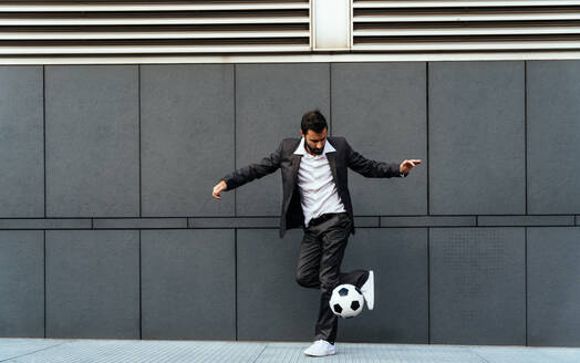 Image of a businessman and soccer freestyle player making tricks with the ball on the street. Concept about sport and business people - DMDF06541