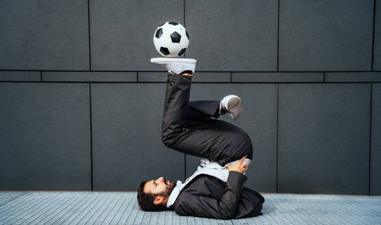 Image of a businessman and soccer freestyle player making tricks with the ball on the street. Concept about sport and business people - DMDF06542