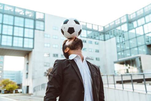 Bild eines Geschäftsmannes und eines Fußball-Freestyle-Spielers, der auf der Straße Tricks mit dem Ball macht. Konzept über Sport und Geschäftsleute - DMDF06545