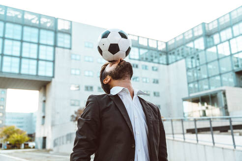 Image of a businessman and soccer freestyle player making tricks with the ball on the street. Concept about sport and business people - DMDF06545