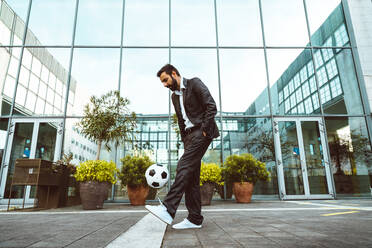 Image of a businessman and soccer freestyle player making tricks with the ball on the street. Concept about sport and business people - DMDF06546