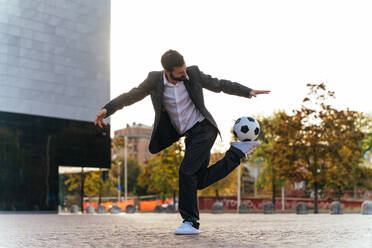 Image of a businessman and soccer freestyle player making tricks with the ball on the street. Concept about sport and business people - DMDF06547