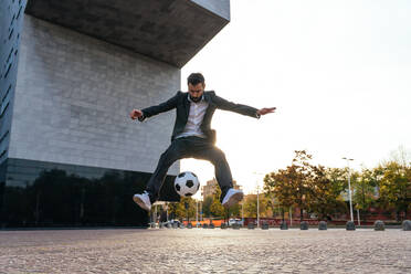 Image of a businessman and soccer freestyle player making tricks with the ball on the street. Concept about sport and business people - DMDF06550