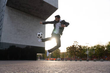 Image of a businessman and soccer freestyle player making tricks with the ball on the street. Concept about sport and business people - DMDF06551