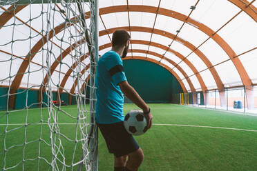 Cinematic Bild eines Fußball-Freestyle-Spieler macht Tricks mit dem Ball auf einem Kunstrasenplatz Indoor. Konzept über Sport und Menschen Lebensstil - DMDF06561