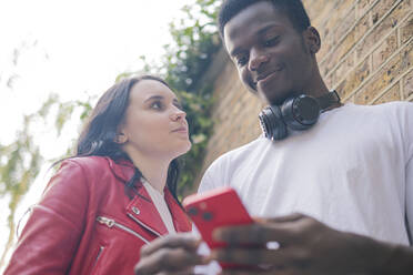 Lächelnde Frau mit Mann, der ein Mobiltelefon benutzt - AMWF01746