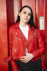 Junge Frau in roter Lederjacke steht vor der Tür - AMWF01759