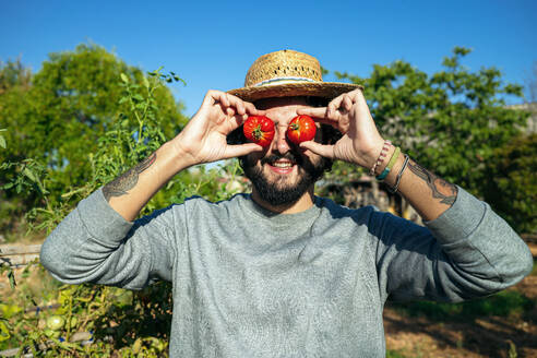 Playful horticulturist placing tomatoes on eyes - GDBF00094