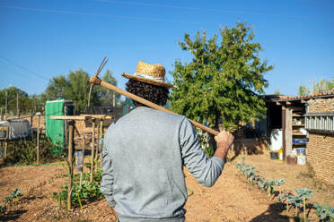 Farmer with hoe on shoulder at farm - GDBF00096