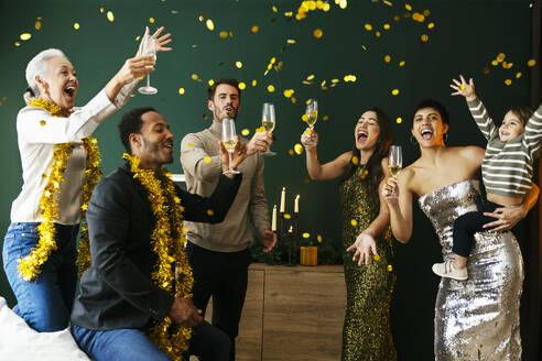 Cheerful family with drinking glasses enjoying new year party at home - EBSF03824