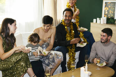 Mehrgenerationen-Familie beim Essen auf der Neujahrsparty im heimischen Wohnzimmer - EBSF03825