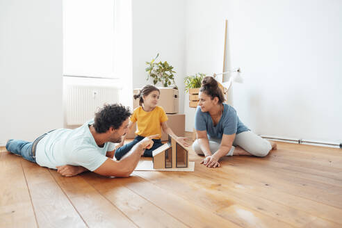 Familie mit Modellhaus auf dem Boden zu Hause - JOSEF21145