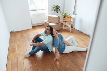 Happy couple sitting on floor at home - JOSEF21151