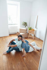 Loving couple sitting on floor at home - JOSEF21154