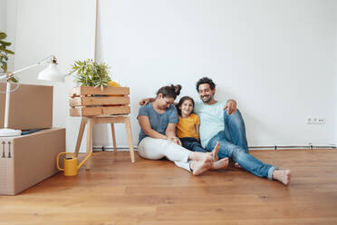 Happy family sitting in front of wall at home - JOSEF21188