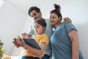 Smiling parents with daughter using tablet PC at home - JOSEF21207