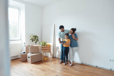 Parents with daughter using tablet PC in front of wall at home - JOSEF21208