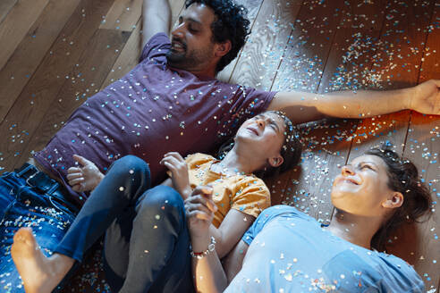Happy parents and daughter having fun with confetti on floor - JOSEF21284