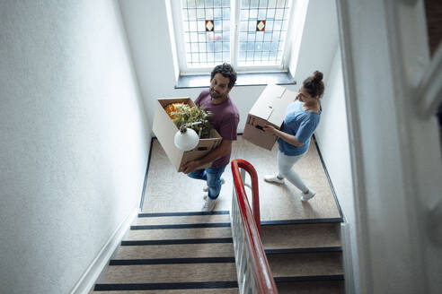 Lächelnder Mann und lächelnde Frau mit Kartons auf der Treppe - JOSEF21287