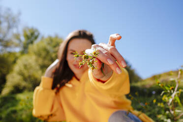 Frau mit Hand im Haar zeigt Blume - MDOF01517