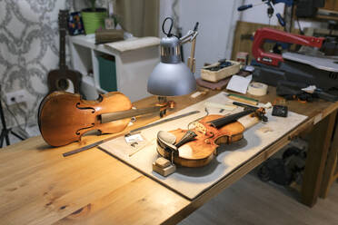 Unfertige Geigen unter der Schreibtischlampe in der Werkstatt - MMPF00972