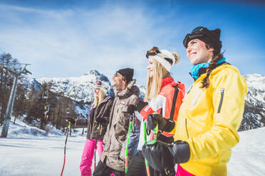 Eine fröhliche Gruppe von Freunden genießt ihren Winterurlaub beim Skifahren im Schnee - DMDF06594