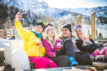 Eine fröhliche Runde genießt das winterliche Ambiente und die Gesellschaft in einem Outdoor-Restaurant während des Skiurlaubs - DMDF06608