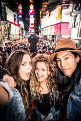 Eine Gruppe von Freunden posiert für ein Selfie auf dem belebten Times Square in Manhattan - DMDF06612