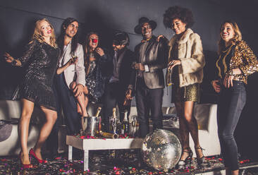 Eine bunte Gruppe von Freunden verschiedener Ethnien feiert ausgelassen in einem Nachtclub - die Clubgänger genießen die Party - DMDF06617