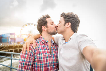 Romantisches Date am Santa Monica-Pier in Los Angeles: Homosexuelles Paar genießt Sonnenuntergang und macht Selfie beim Kuss - DMDF06629