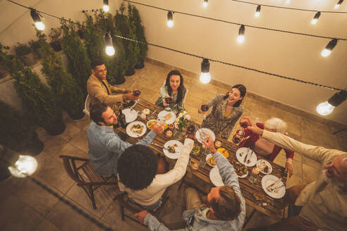 Erzählende Aufnahmen einer multiethnischen Gruppe von Menschen, die auf einer Dachterrasse speisen. Familie und Freunde treffen sich zu Hause - DMDF06681
