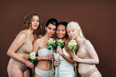 Beauty image of a group of women with different age, skin and body posing  in studio for a body positive photoshooting. Mixed female models in lingerie  on colored backgrounds stock photo