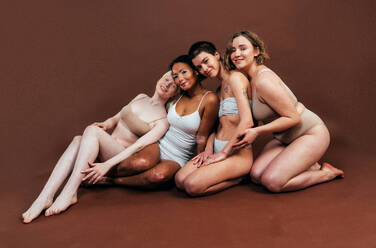 Eine Gruppe von Frauen mit unterschiedlicher Hautfarbe posiert gemeinsam im Studio, um das Konzept der Körperfreundlichkeit und Selbstakzeptanz zu fördern - DMDF06708