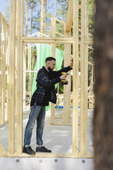 Ingenieur beim Bohren von Holz mit Arbeitsgerät auf der Baustelle - SEAF02009