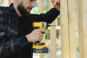 Arbeiter bohrt Holz auf einer Baustelle - SEAF02010