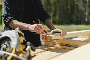 Ingenieur misst Holz auf der Baustelle an einem sonnigen Tag - SEAF02024