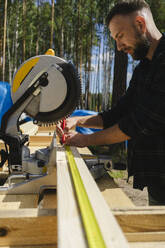 Blue-collar worker measuring plank on sunny day - SEAF02029