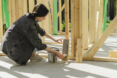 Arbeiter, der auf einer Baustelle eine Planke mit einem Pinsel streicht - SEAF02031