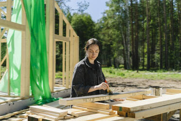 Arbeiter beim Streichen von Brettern auf einer Baustelle an einem sonnigen Tag - SEAF02035